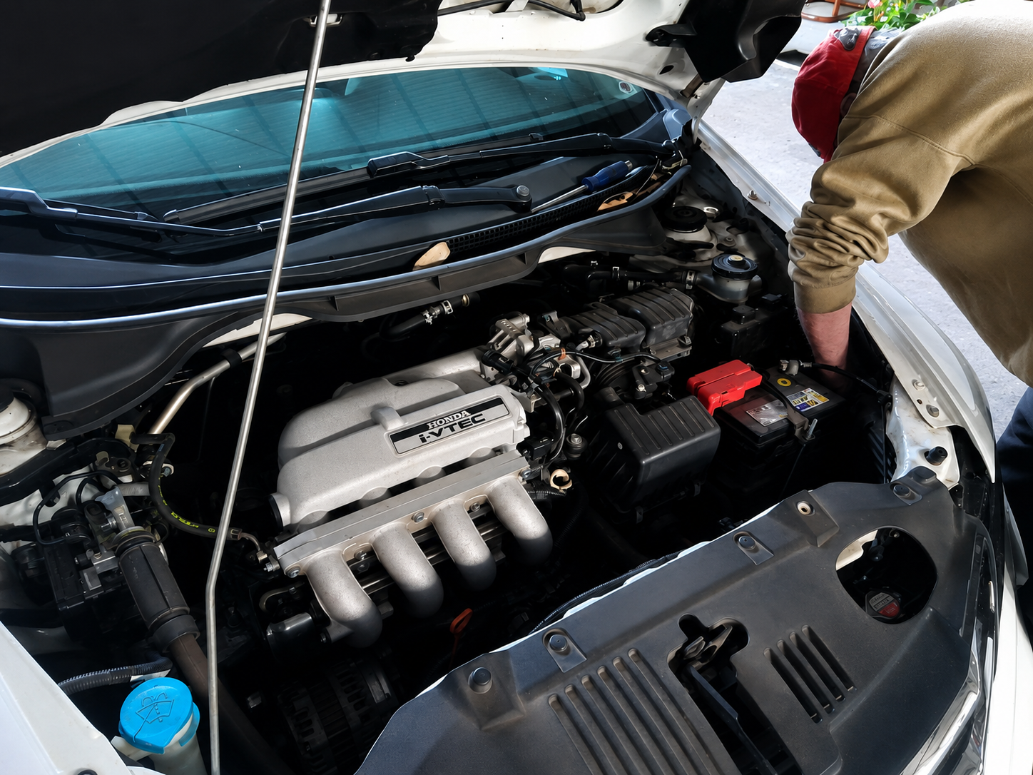 Funcionário realizando manutenção no motor de um veículo Honda